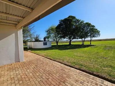 a brick walkway leading to a yard with trees at Oudezwaanskraal Game Farm in Waaikraal
