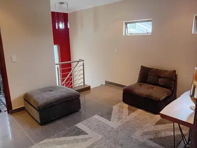 a living room with a chair and a ottoman at 4C On Gillian in Sandton
