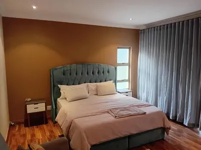 a bedroom with a large bed with a green headboard at 4C On Gillian in Sandton