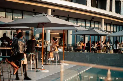 a group of people sitting at tables with umbrellas near a pool at 2115 Kepler, Ellipse - Serene Luxury in Midrand