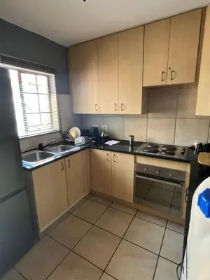 a kitchen with wooden cabinets and a sink and a stove at 2 Spacious bedroom apartment in Ellisras
