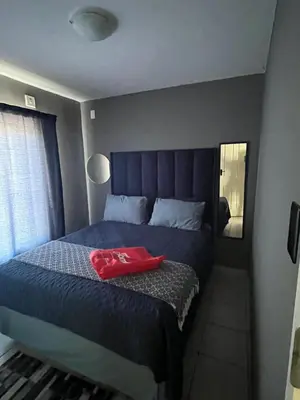 a bedroom with a blue bed with a red bag on it at 2 Spacious bedroom apartment in Ellisras