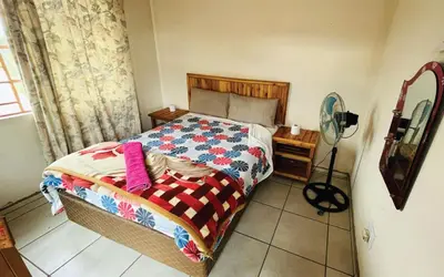 a bedroom with a bed and a fan at Malala Lodge in Lorraine
