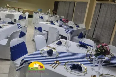 a room with white tables with blue and white chairs at Malala Lodge in Lorraine