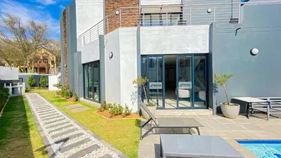 a building with a patio with benches and a pool at Binbin Home Away From Home in Midrand
