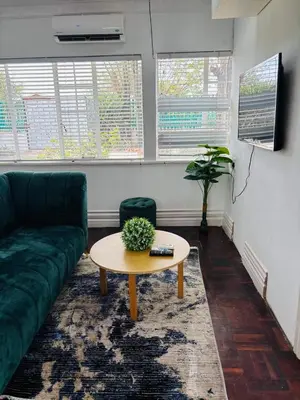 a living room with a green couch and a table at Tabularasa Hideaway in Pretoria