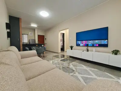 a living room with two couches and a flat screen tv at Ridge Comfort in Midrand