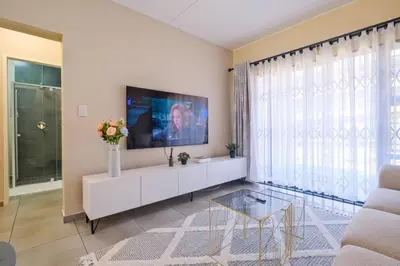 a living room with a tv and a white cabinet at Ridge Comfort in Midrand
