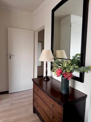 a room with a dresser with a lamp and a mirror at Gallery Grove in Pretoria