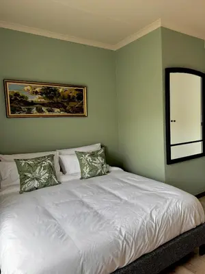 a bedroom with a white bed with a window at Gallery Grove in Pretoria