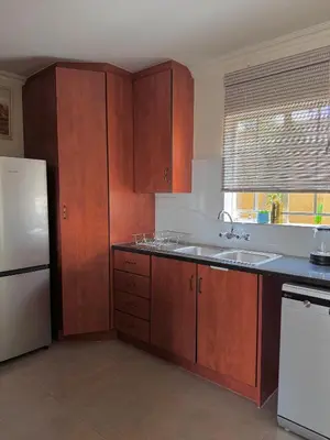 a kitchen with wooden cabinets and a white refrigerator at Gallery Grove in Pretoria