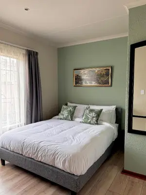 a bedroom with a large bed with green walls at Gallery Grove in Pretoria