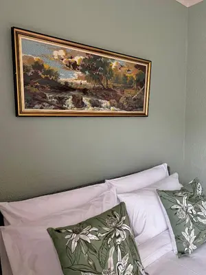 a painting on the wall above a bed with pillows at Gallery Grove in Pretoria