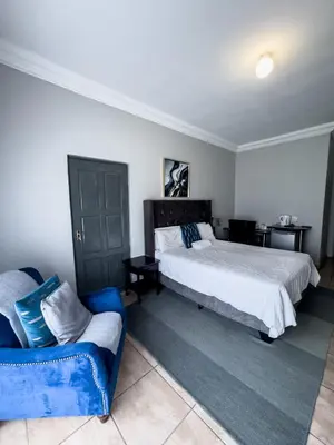 a bedroom with a bed and a blue couch at Bobisemo Luxury Guesthouse in Tierpoort
