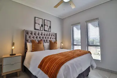 a bedroom with a large bed and two windows at Lethukukhanya Luxury Apartment in Nelspruit
