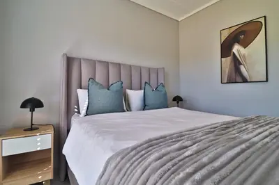 a bedroom with a large bed with blue pillows at Lethukukhanya Luxury Apartment in Nelspruit
