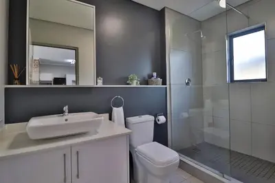 a bathroom with a toilet and a sink and a shower at Lethukukhanya Luxury Apartment in Nelspruit