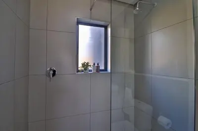 a bathroom with a glass shower with a window at Lethukukhanya Luxury Apartment in Nelspruit
