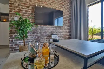 a living room with a table and a brick wall at Lethukukhanya Luxury Apartment in Nelspruit