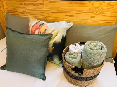 a basket of towels sitting on a bed with pillows at The Hideaway Cabin in Pretoria