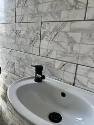 a white sink in a bathroom with marble tiles at The Hideaway Cabin in Pretoria