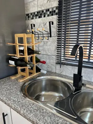 a kitchen counter with a sink and wine bottles at The Hideaway Cabin in Pretoria