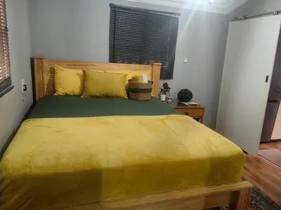 a bedroom with a large bed with a yellow blanket at The Hideaway Cabin in Pretoria