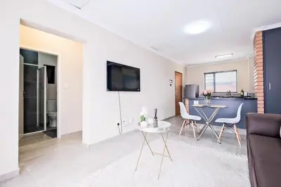 a living room with a table and chairs and a kitchen at Diamond Hill in Midrand