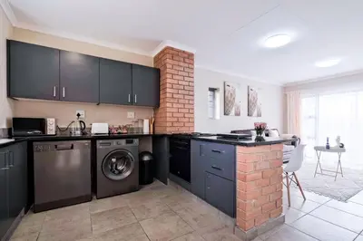 a kitchen with black cabinets and a washer and dryer at Diamond Hill in Midrand