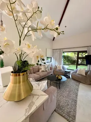 a living room with a large gold vase with white flowers at Pecanwood Paradise in Hartbeespoort
