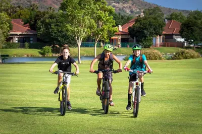 three people riding bikes on a grass field at Pecanwood Paradise in Hartbeespoort