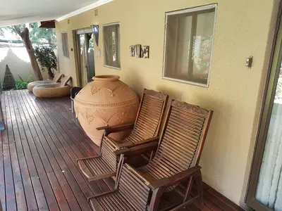 two chairs sitting on a porch with a large vase at Santai guesthouse in Brits