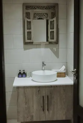 a bathroom with a white sink and wooden cabinets at Santai guesthouse in Brits