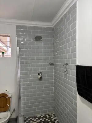 a bathroom with a shower with blue tiles at Soft Spaces Haven in Pretoria