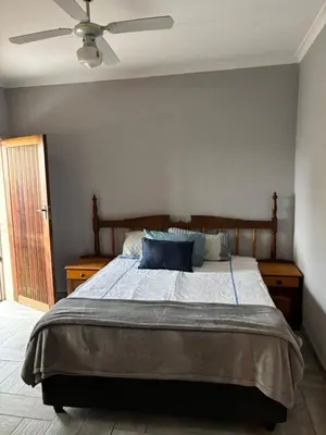 a bedroom with a large bed with a ceiling fan at Soft Spaces Haven in Pretoria