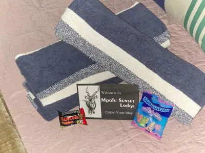a blue and white blanket on a bed with a book at The Big Rondawel in Marloth Park