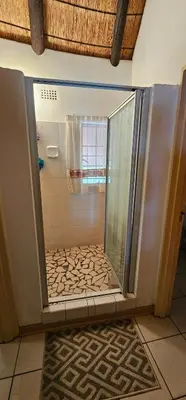 a shower with a glass door in a bathroom at The Big Rondawel in Marloth Park