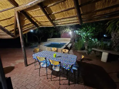 a table and chairs in a patio with a pool at The Big Rondawel in Marloth Park