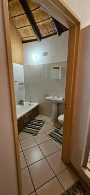 a bathroom with a tub and a toilet and a sink at The Big Rondawel in Marloth Park