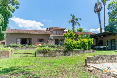 a house with palm trees and a yard at The Orange Tree Guest House in Nelspruit