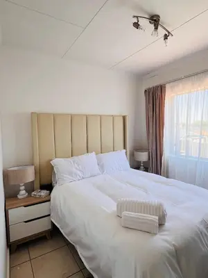a bedroom with a large white bed and a window at The Lux apartment in Polokwane