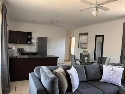 a living room with a couch and a kitchen at The Lux apartment in Polokwane