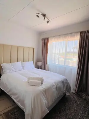 a bedroom with a large white bed with a window at The Lux apartment in Polokwane