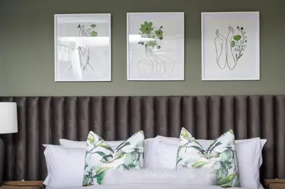 a bedroom with four pictures above a bed with pillows at Polka Dot Airport Exec Suite in Kempton Park