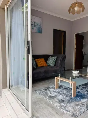 a living room with a couch and a glass table at Hideaway Haven in Pretoria