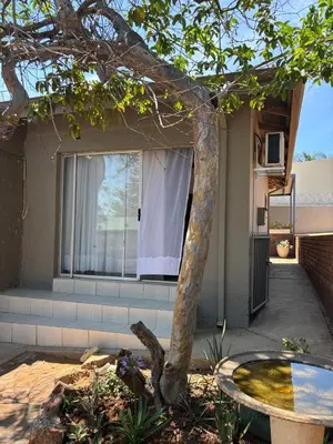 a tree in front of a house with a table at Hideaway Haven in Pretoria