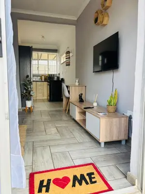 a living room with a tv and a rug on the floor at Hideaway Haven in Pretoria