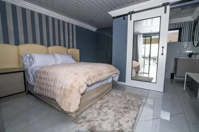 a bedroom with a large bed and a mirror at The Fine Line Lodge in Pretoria