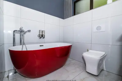 a red bath tub in a bathroom with a toilet at The Fine Line Lodge in Pretoria