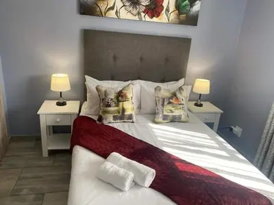 a bedroom with a large white bed with two lamps at Morodi Guest Lodge in Witbank